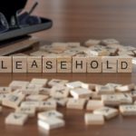 Leasehold Word Or Concept Represented By Wooden Letter Tiles On A Wooden Table With Glasses And A Book