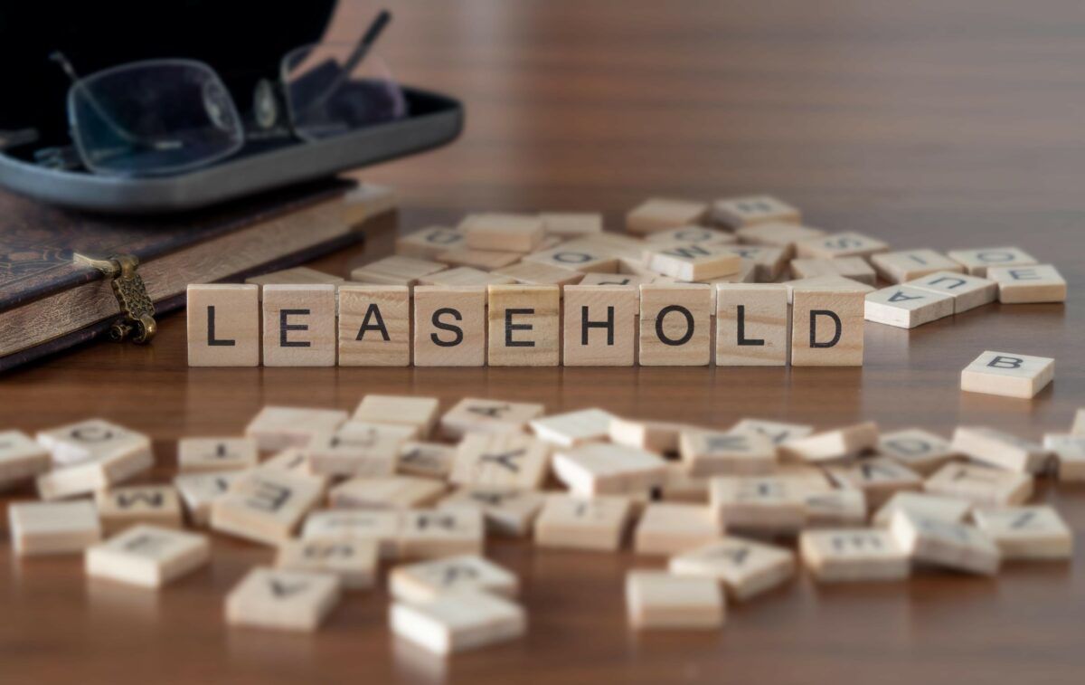 Leasehold Word Or Concept Represented By Wooden Letter Tiles On A Wooden Table With Glasses And A Book